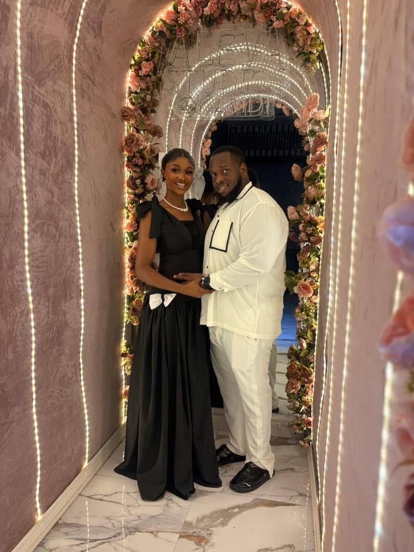 Gabrielle and Ifeanyi beneath a flower-lit archway